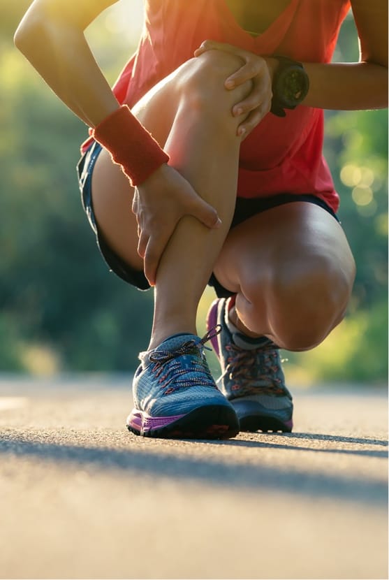 Woman kneeling in street with hands on knee and shin