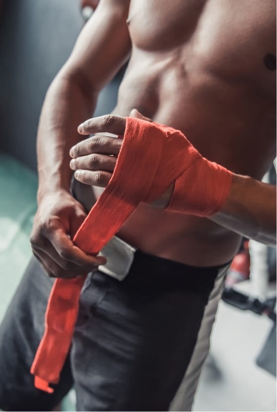 Shirtless man wrapping hand at the gym