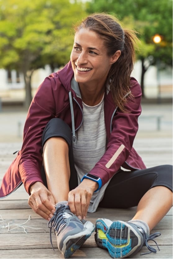 Woman sitting outside adjusting her shoe after a run