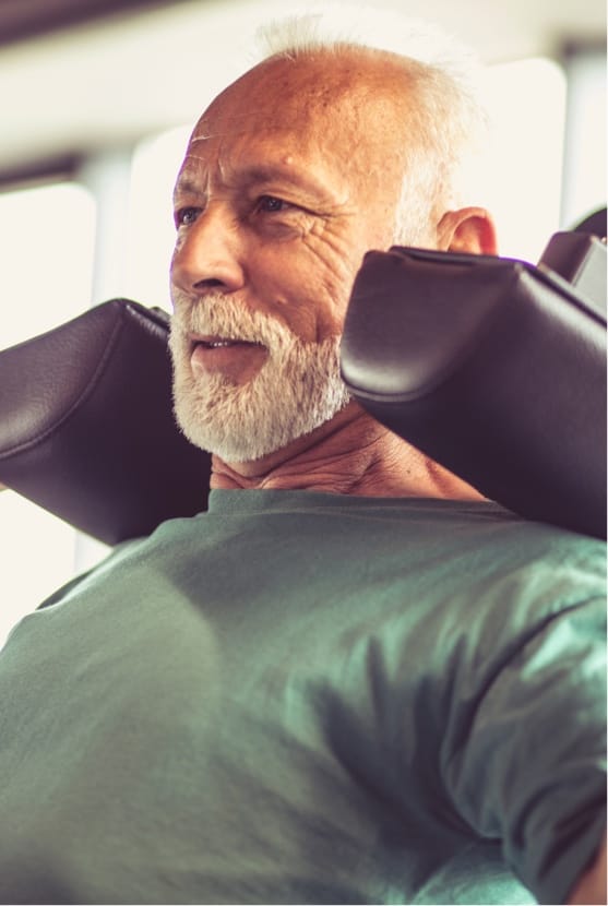 Older man at a gym using a workout machine