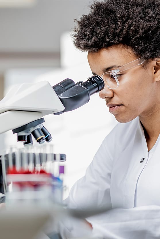 Lab technician looking into microscope lens