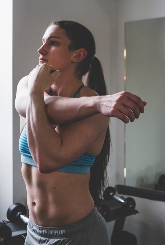 Woman stretching arm across chest at a gym