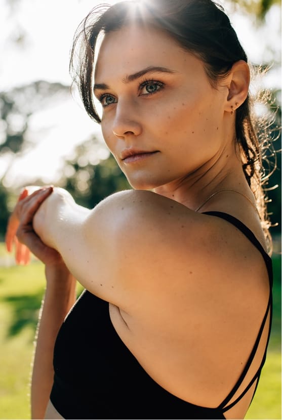 Woman stretching arm across body outside