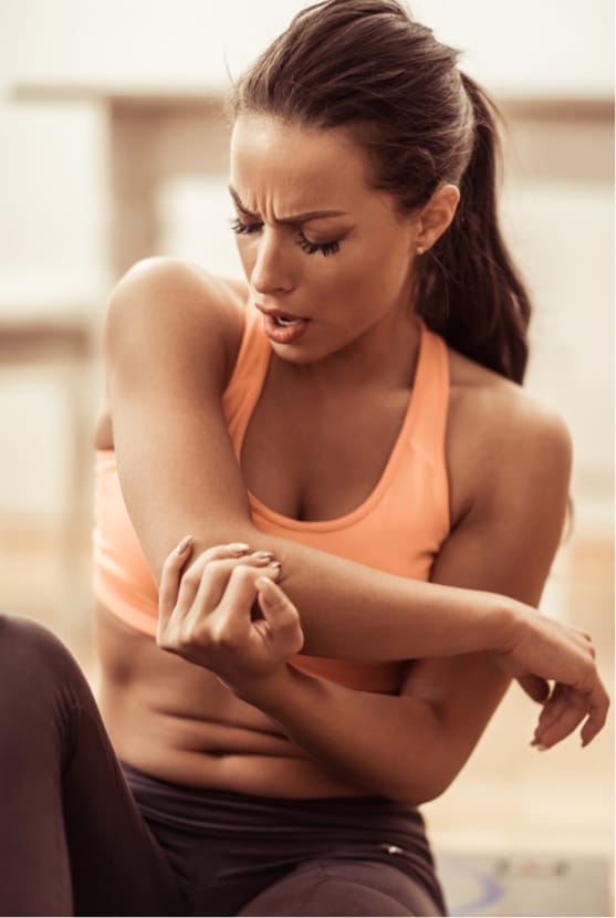 Woman in workout clothes grabbing elbow in pain